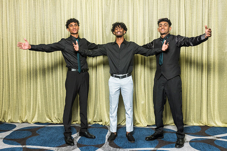 Male students at school formal photographed against a gold backdrop