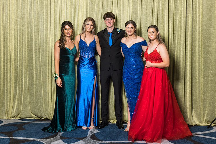 Group photo of male and female students at school formal photographed against a gold backdrop