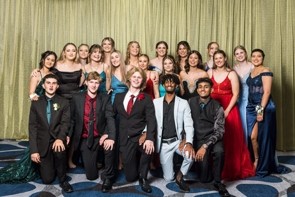Group photo of male and female students at school formal photographed against a gold backdrop
