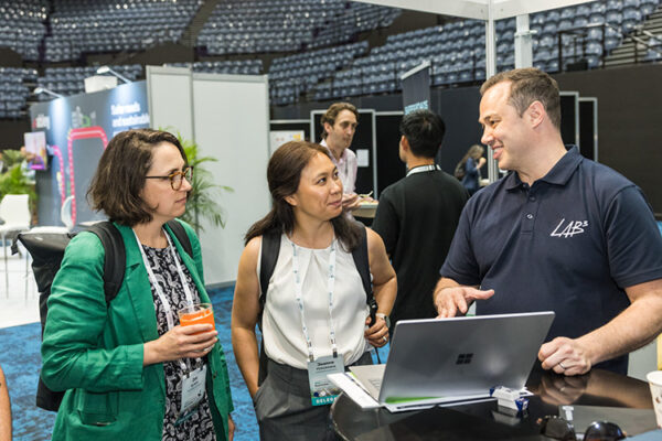 A trade show exhibitor showing delegates info on a laptop