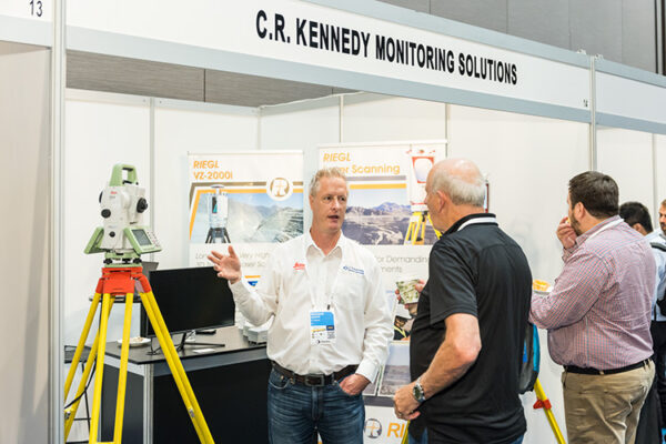 Exhibitor talking to delegates in front of trade exhibit booth at conference