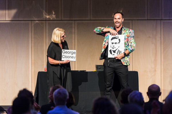 Comedian and member of audience on stage at conference dinner