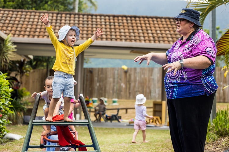 A young boy roaring like a lion as an educator looks on at a childcare centre