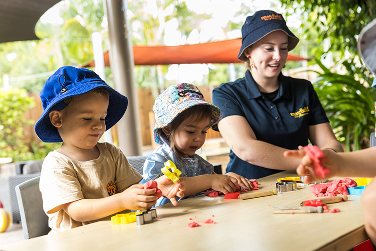 Children playing with play doh with an early childhood educator