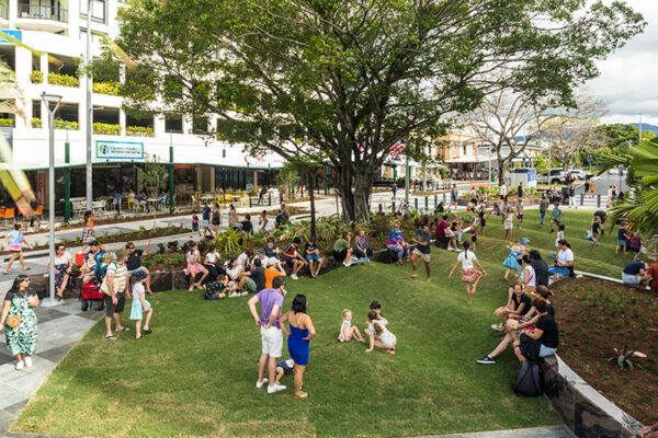 Kids and parents playing on wave-like grass mounds on street facade