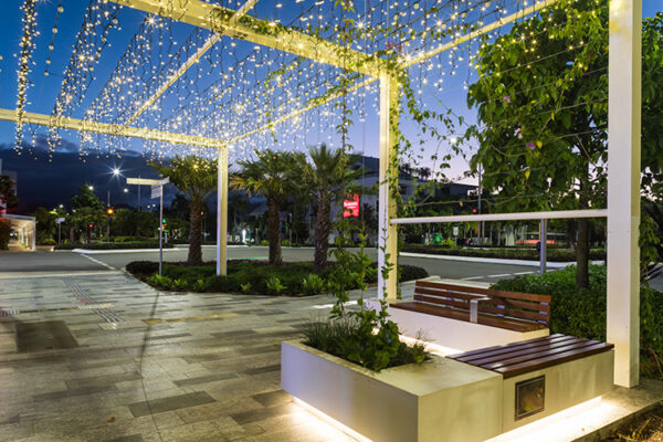 Pedestrian walkway under pergola fitted with lights at twilight