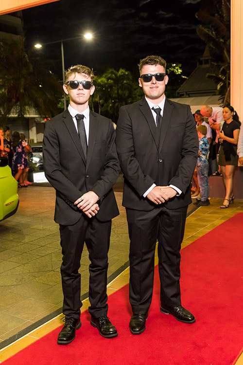 Young male students dressed up on red carpet for school formal arrivals