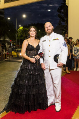 A Navy officer and daughter dressed up on red carpet for school formal arrivals