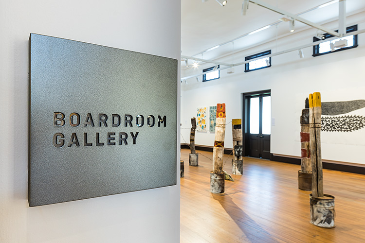 Board Gallery sign with indigenous artwork exhibition in backgroun