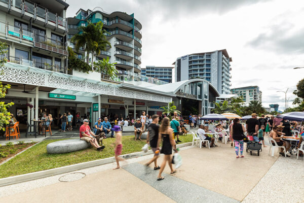 People walking and seated along Esplanade promenade with cafes in background