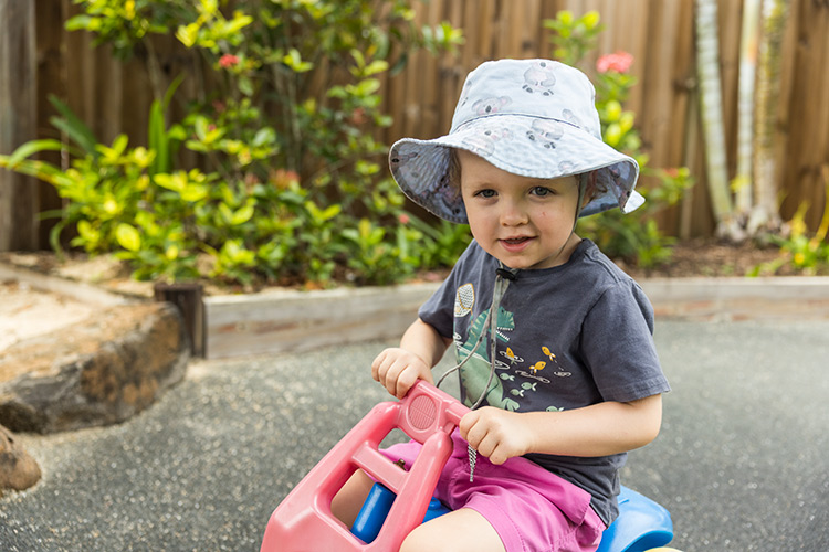 A young boy riding a tricycle at an early learning centre