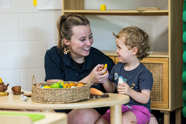 A female early learning educator playing with a young boy at a childcare centre