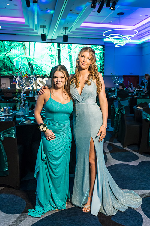 Group of female students dressed up for senior formal with ballroom backdrop