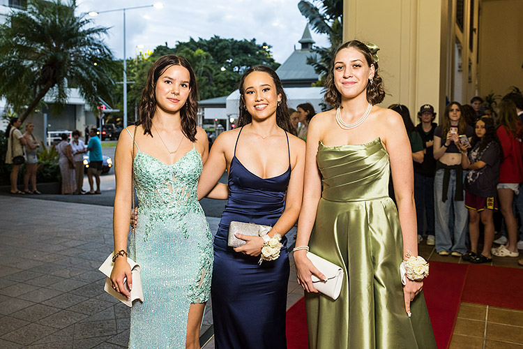 Female students dressed up on red carpet for school formal arrivals