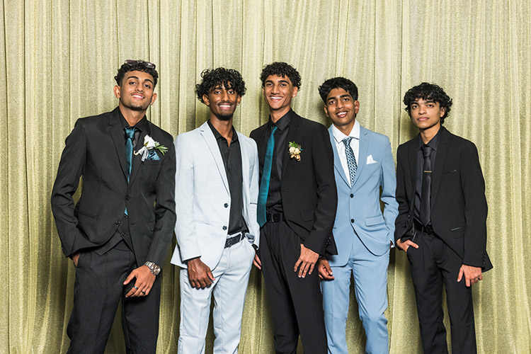 Male students at school formal photographed against a gold backdrop