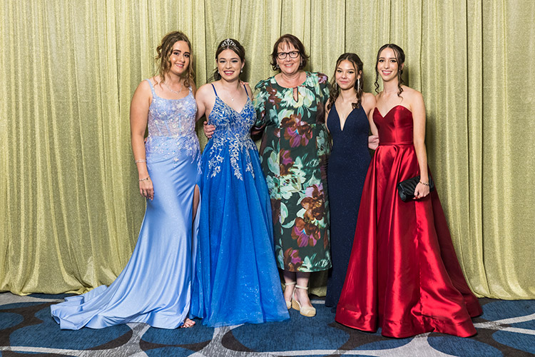 Group photo of female students and teacher at school formal photographed against a gold backdrop