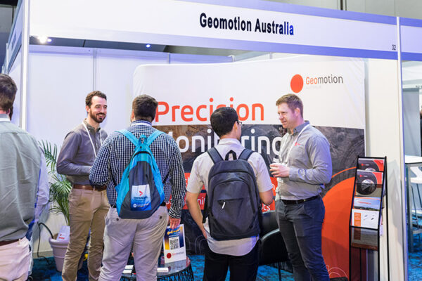 People talking in front of trade exhibit booths at conference