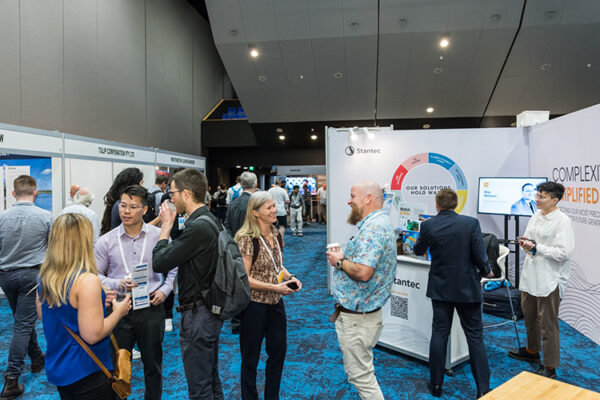 People talking in front of trade exhibit booths at conference