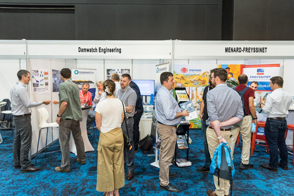 People talking in front of trade exhibit booths at conference
