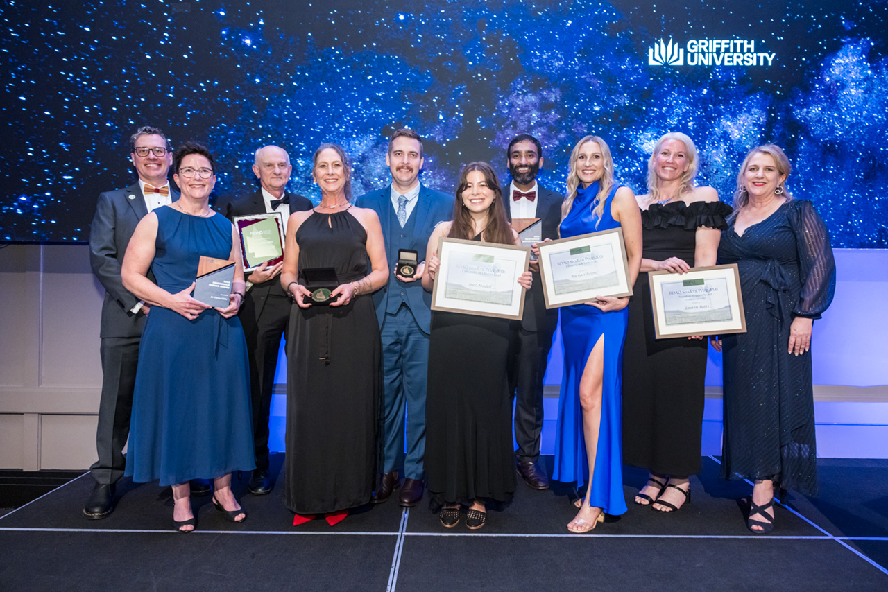 Group photo of award winners on stage holding their awards